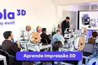 An Escola 3D class in progress, a room of people at 3D printers with the course slide on screen.